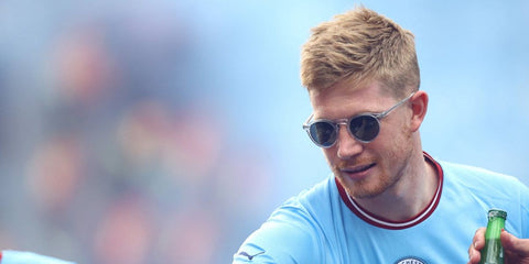 Manchester City player Kevin de Bruyne was seen wearing transparent Oliver Peoples Gregory Peck Sun OV5217S 1101/R8 sunglasses with blue Indigo Photochromic lenses