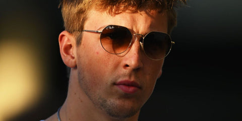 New Zealand racer Liam Lawson was seen wearing gold Ray-Ban Jack RB 3565 001/51 round sunglasses with brown gradient lenses at the Formula 1 testing in Abu Dhabi, December 2025.